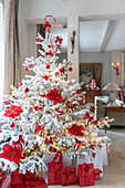 White Christmas tree decorated with poinsettias and red baubles