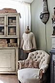 A comfortable upholstered armchair, a tailor's dummy and a shabby chic-style dresser