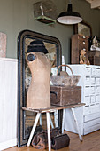 A dressmaker's dummy, a wooden box and a basket in front of an old mirror