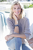 A young blonde woman wearing a light-coloured jumper and jeans