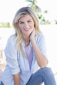 A young blonde woman wearing a purple t-shirt and a blue-and-white striped shirt