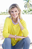 A young blonde woman wearing a yellow jumper and jeans