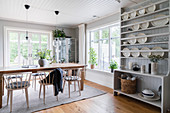 Helles Tellerregal aus Holz und Esstisch mit Stühlen in offenem Wohnraum