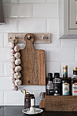 A wooden box of spices, a wooden board and a garlic plait on a wall