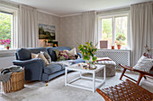 A coffee table and a blue upholstered sofa in a living room with patterned wallpaper