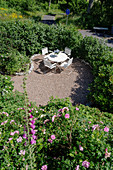 A round table and chairs on a terrace in a sunny garden