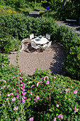 Terrassenplatz mit rundem Tisch und Stühlen in sonnigem Garten