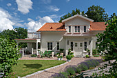 Weißes Holzhaus mit sonnigem Garten