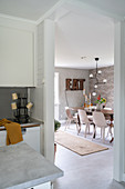 A view from a kitchen into a dining room with an antique table and the word 'EAT' on the wall in illuminated letters