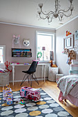 A desk with a chair in a girl's room with toys on the carpet in the foreground