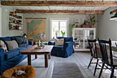 An upholstered two-piece suite with blue covers, a coffee table and a cabinet in a rural-style living room