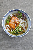 Salmon in a vung-tau vegetable broth with an onion and cucumber medley, and rice noodles