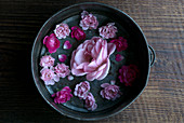 Rosa Rosenblüten im Vintage Topf auf rustikalem Holzuntergrund