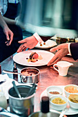 A waiter take a plate from the pass in a restaurant