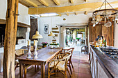 Wooden table with rattan chairs in country kitchen with wood-beamed ceiling