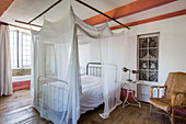 Bed with canopy in bedroom with rustic wooden floorboards