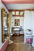Wandspiegel, Beistelltisch und Waschbecken im Schlafzimmer mit rustikaler Holzdielenboden