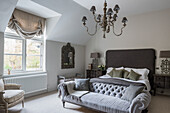 Master bedroom with buttoned back sofa, chandelier, table lamps and headboard