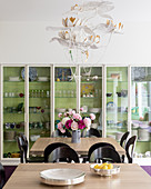 Glass fronted cabinet with pair of oak topped tables and vintage chairs allow 16 to be seated for dinner