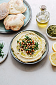 Hummus sprinkled with chickpeas and parsley served with pita bread