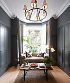 Small living room with grey fitted cupboards and sofa in bay window