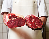 Butcher holds roast beef and entrecôte