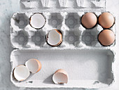Brown eggs and eggshells in an egg box