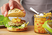A fish burger with a pineapple and chilli chutney being plated
