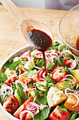 Colourful tomato salad being drizzled with a balsamic dressing