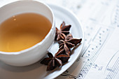 Nahaufnahme einer Tasse Tee mit Sternanis auf Notenblatt