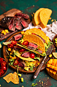Shells of tacos with beef, avocado, mango, arugula and cherry tomatoes