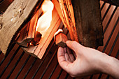 A burning fire starter being added to wood