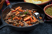 Gebratenes Karottengemüse mit Pilzen in gusseiserner Pfanne