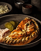 Closed pizza 'Calzone' with chicken and pickled cucumbers