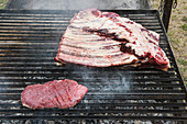 Raw beef ribs and steak on a grilling rack
