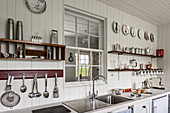 Küchenutensilien auf Regalen und Innenfenster in einer renovierten Küche mit Holzverkleidung