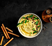 Hummus peas placed on a bowl near crackers on dark background