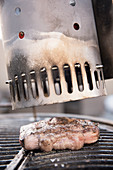 Grilling steak on a grate above a fireplace