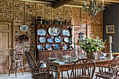 Decorative chinaware on antique wooden dresser with table and chairs in restored 16th century farmhouse