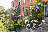 Folding table and chairs in garden of brick 16th century farmhouse