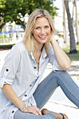 A blonde woman wearing a light-blue striped shirt and jeans
