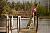 Serene man standing at railing of dock