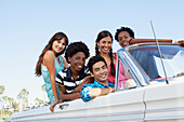 Smiling friends sitting in convertible