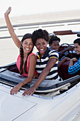 Smiling women cheering in convertible