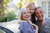 Older couple hugging granddaughter