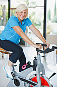 Older woman riding exercise bike in home