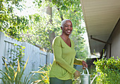 Older woman watering plants in backyard