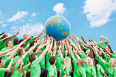 Team in green t-shirts lifting globe
