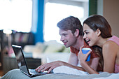Couple using laptop together on bed