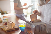 Woman putting bread in toaster